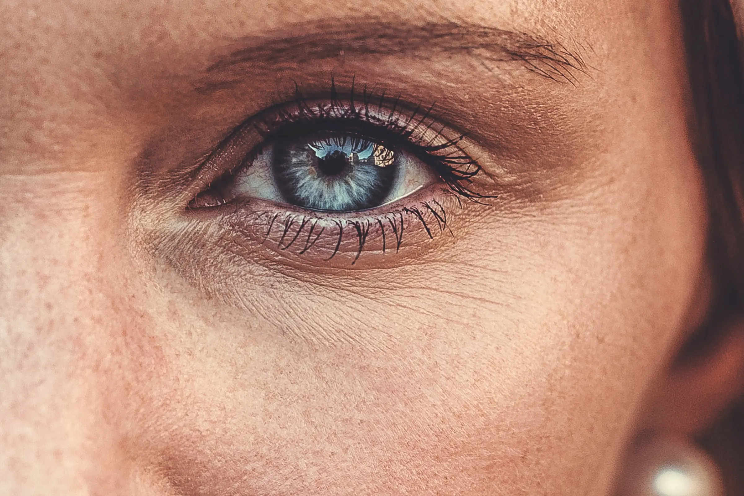 Makroaufnahme eines blauen Auges mit Sommersprossen