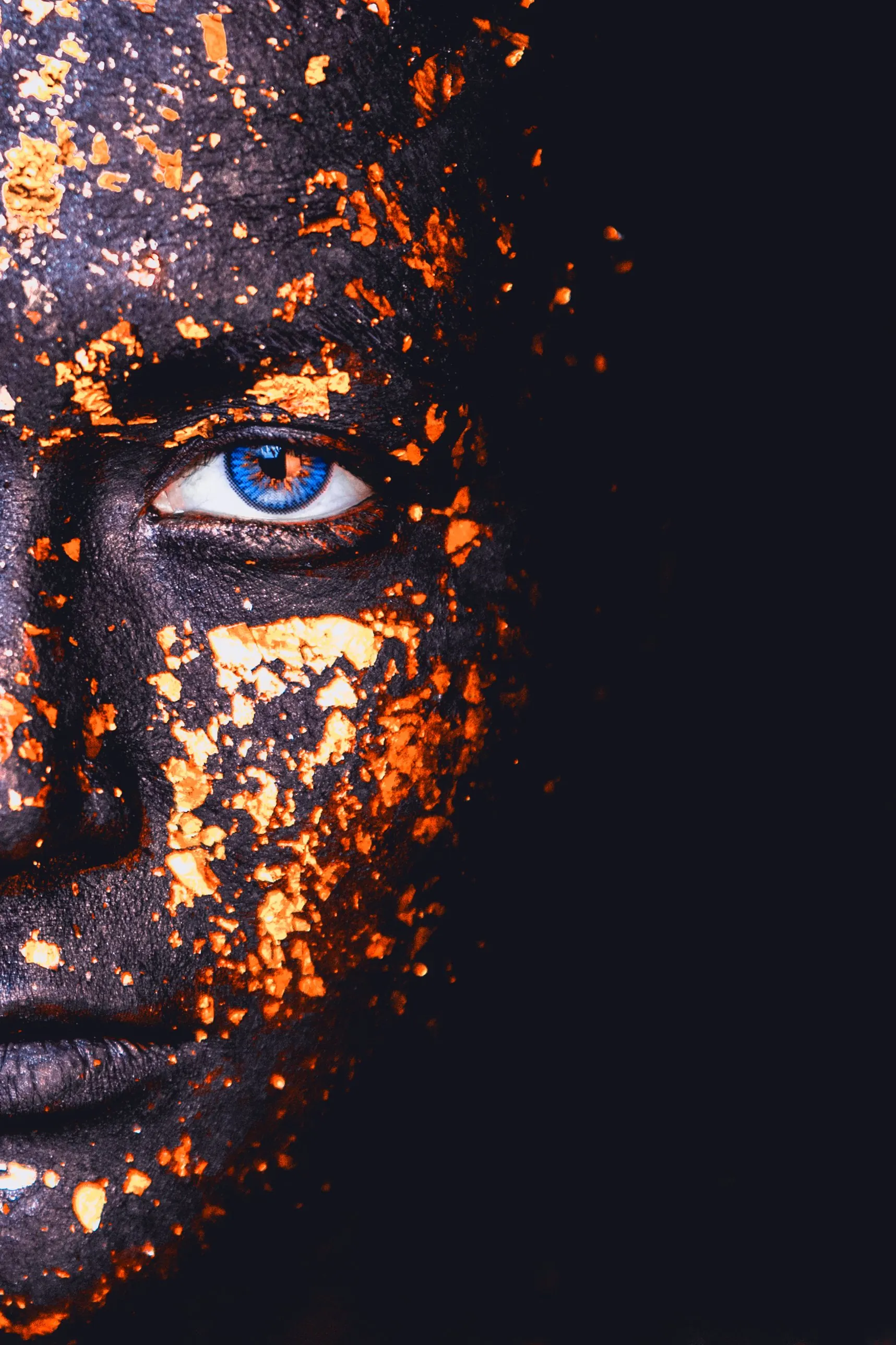Beauty-Porträt: halbes Gesicht mit Blattgold und blauem Auge vor dunklem Hintergrund