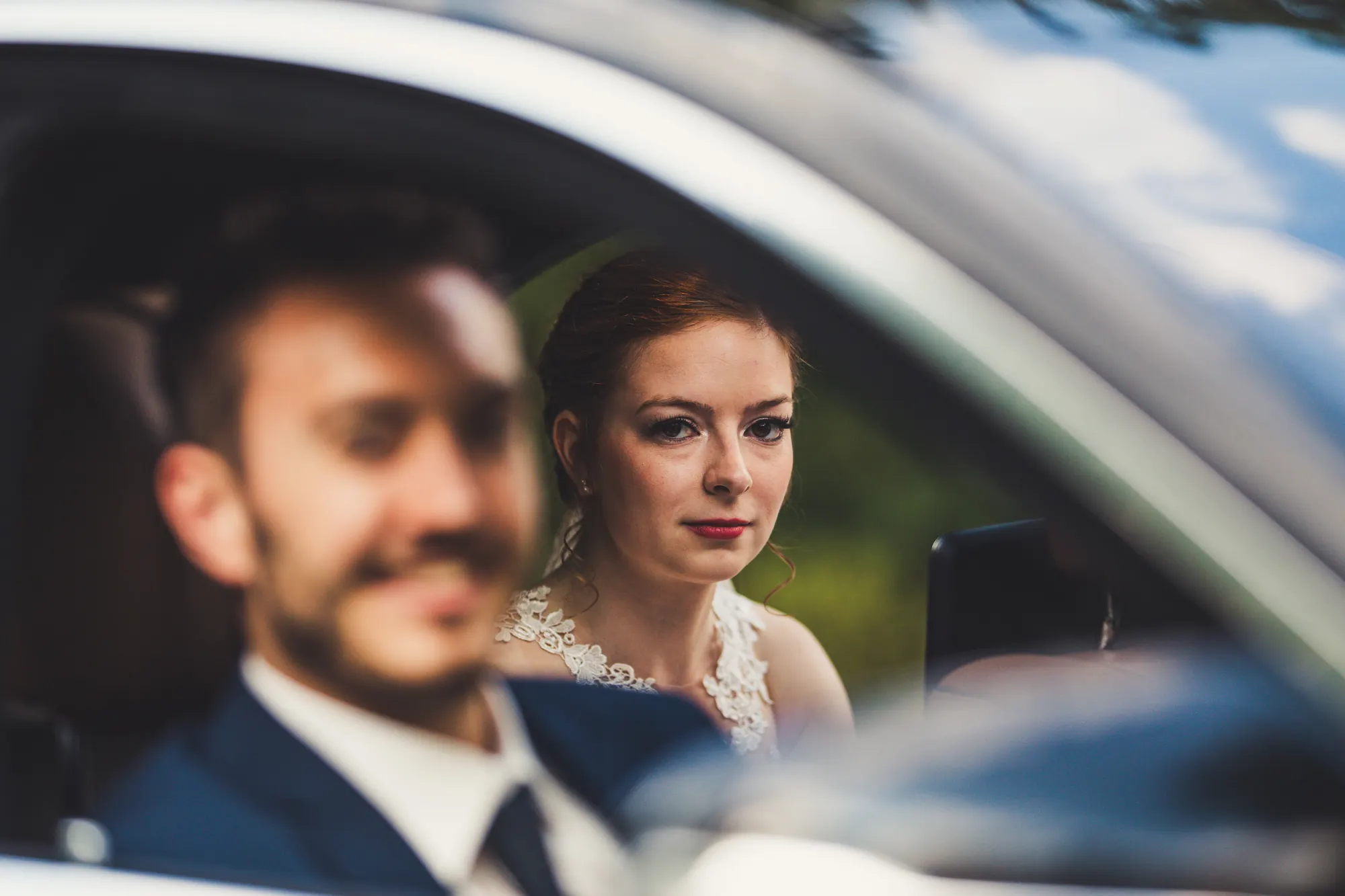 Braut im Hochzeitsauto, durch das Fenster fotografiert