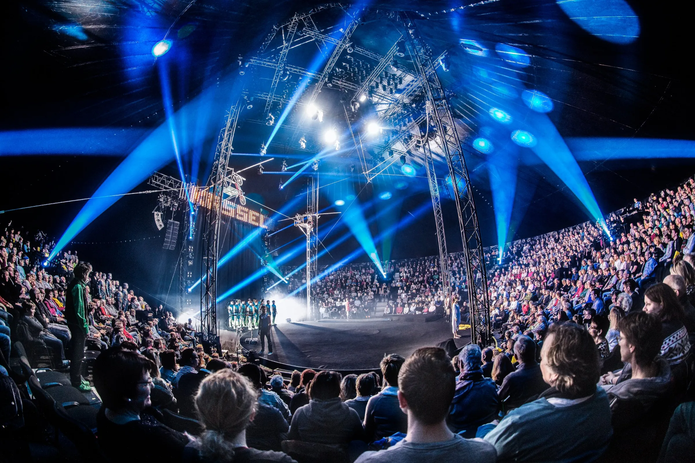 Eventfotografie: Show im Zirkuszelt mit blauem Bühnenlicht und Publikum