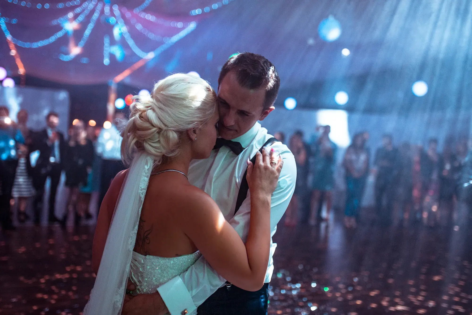 Hochzeitstanz des Brautpaars im Lichtregen, Gäste im Hintergrund