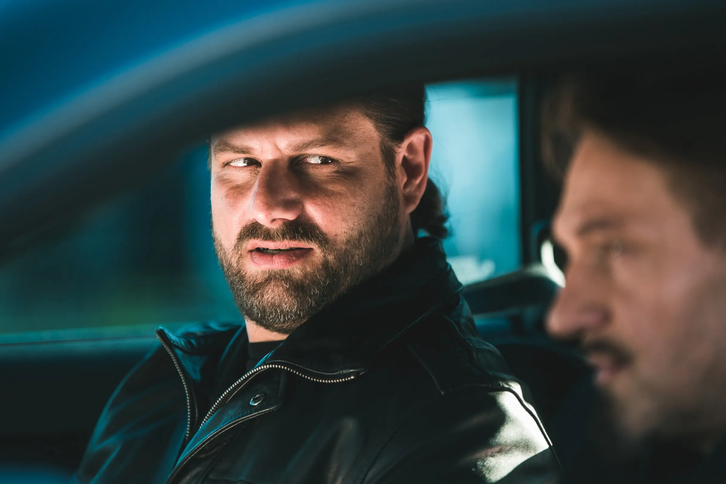 Filmstill: Mann in Lederjacke im Auto