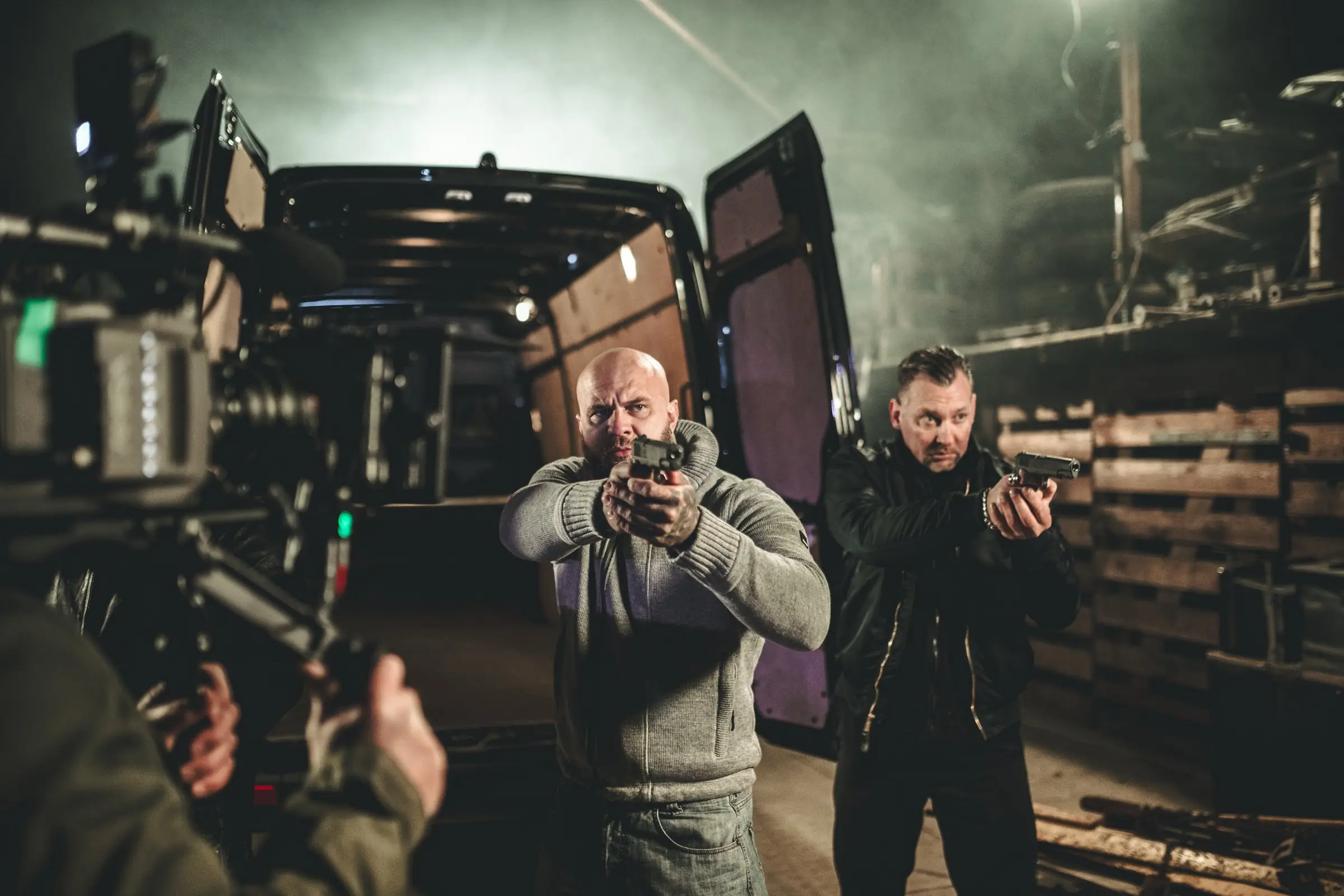 Behind the Scenes: Actionszene vor einem Transporter, im Vordergrund die Filmkamera