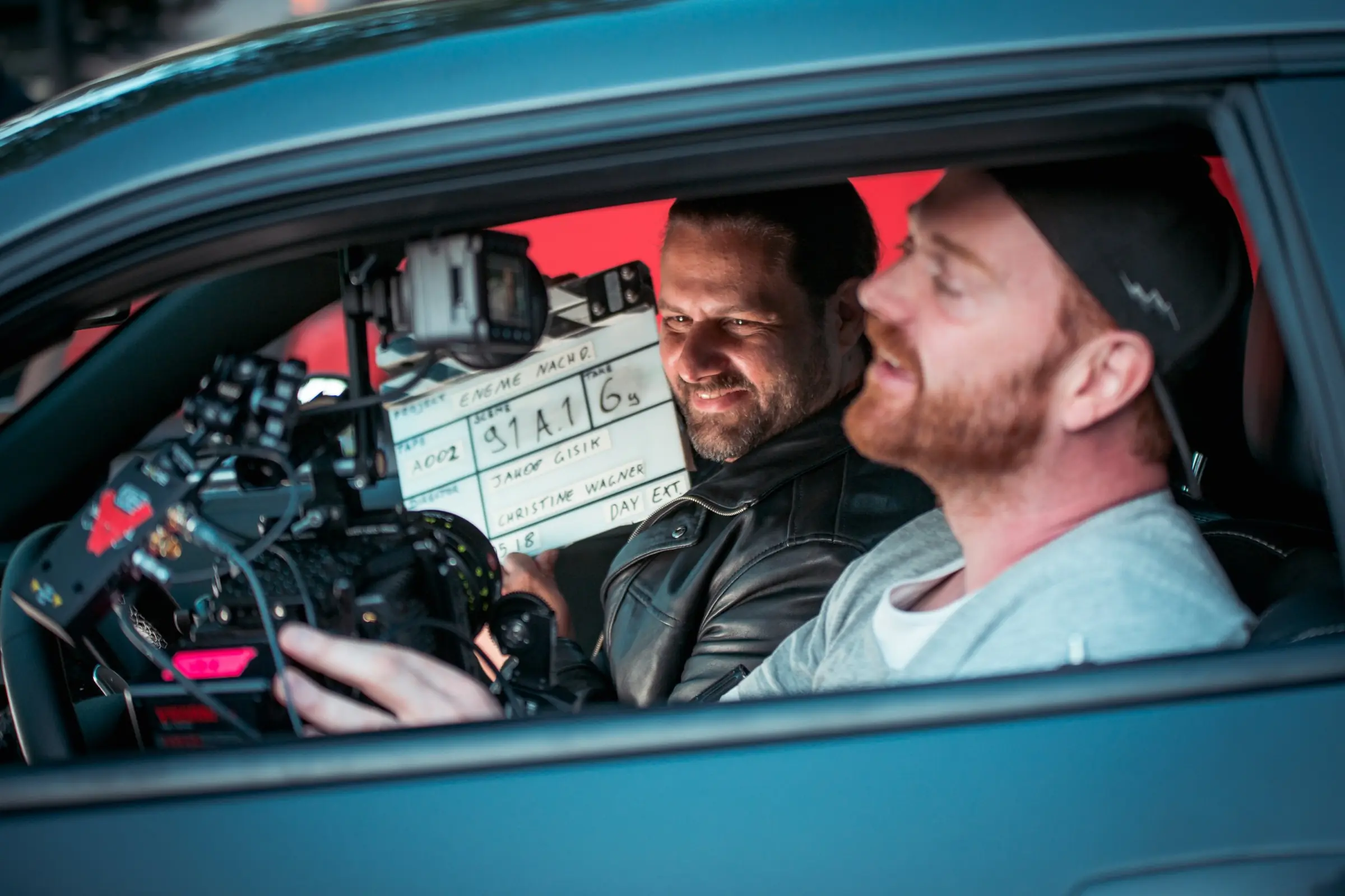 Standfotografie am Filmset von „EneMe“: Darsteller im Auto mit Filmklappe, davor die Kamera