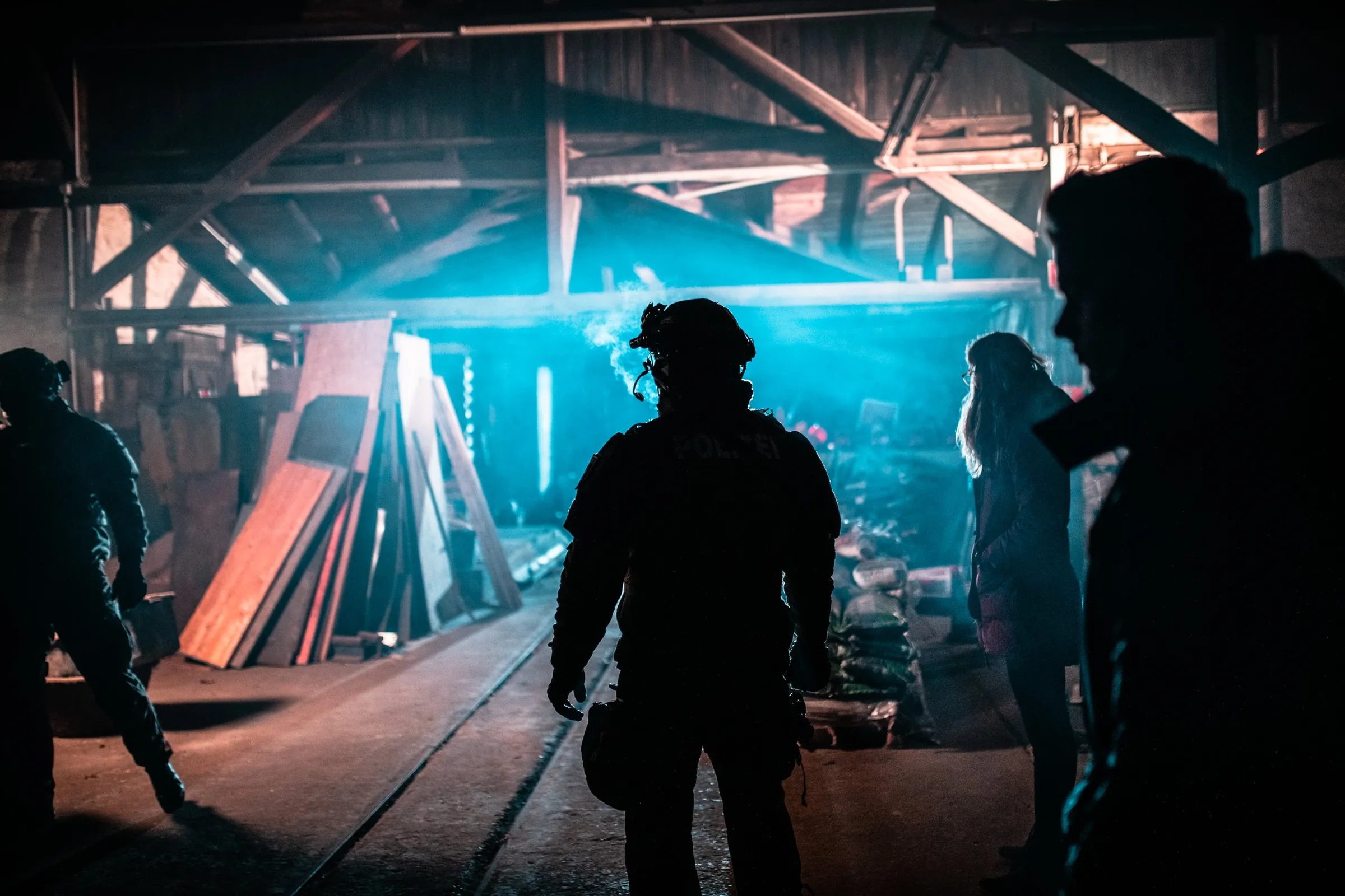 Standfotografie am Filmset: Silhouetten von Darstellern in Einsatzkleidung in einer Halle mit blauem Gegenlicht und Nebel
