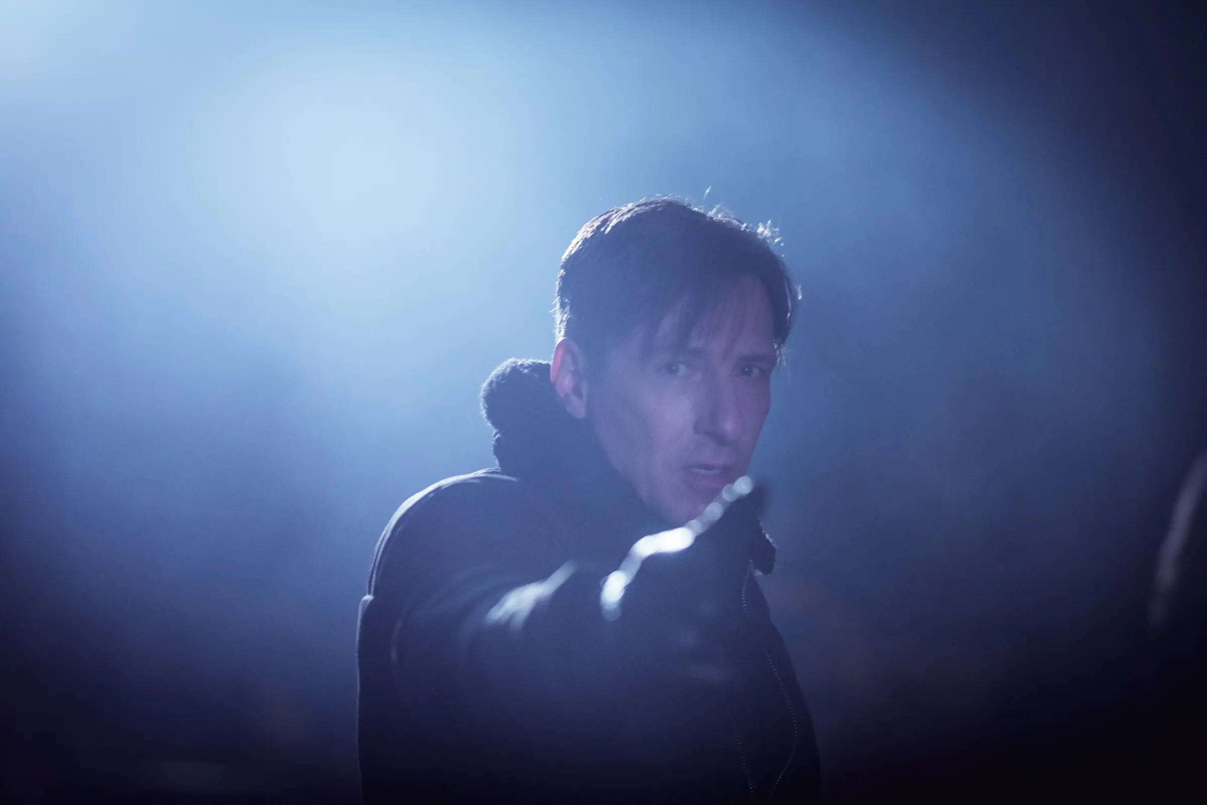 Filmstill: Darsteller im blauen Gegenlicht und Nebel